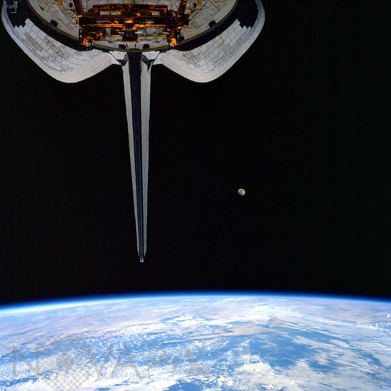 Shuttle Discovery above Earth with moon. 12/1999